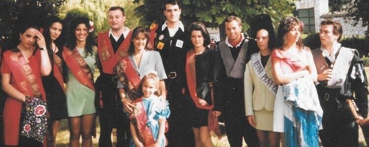 Grupo de personas, probablemente con atuendo formal, al aire libre. Algunas llevan fajas y sonríen.