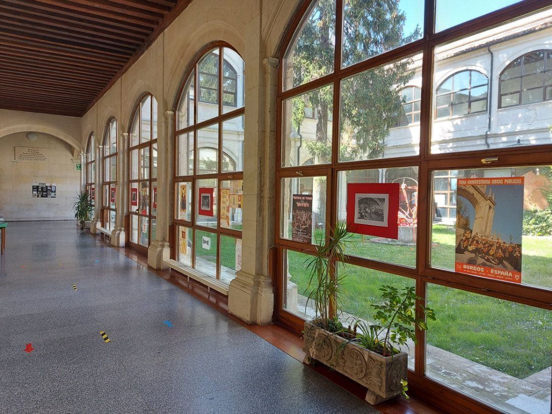 Pasillo largo con ventanas arqueadas que exhiben arte enmarcado y vistas a un patio cubierto de césped.