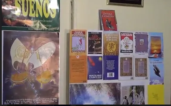 Libros expuestos en una pared, algunos con portadas y lomos coloridos. Debajo hay un póster de 