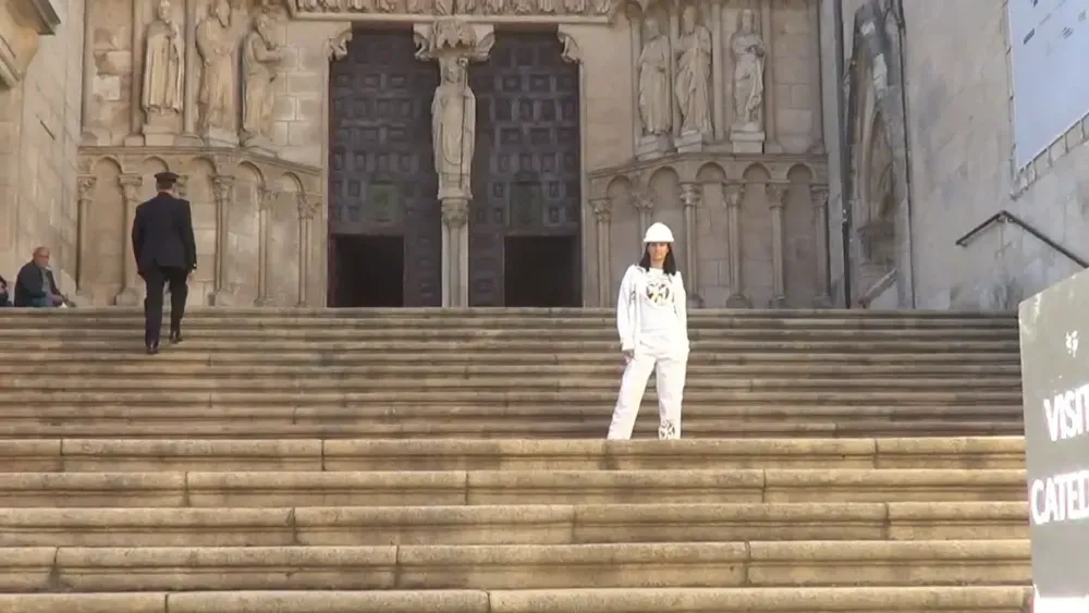 Una mujer vestida de blanco se encuentra en los escalones de una catedral, un hombre vestido de negro sube las escaleras.