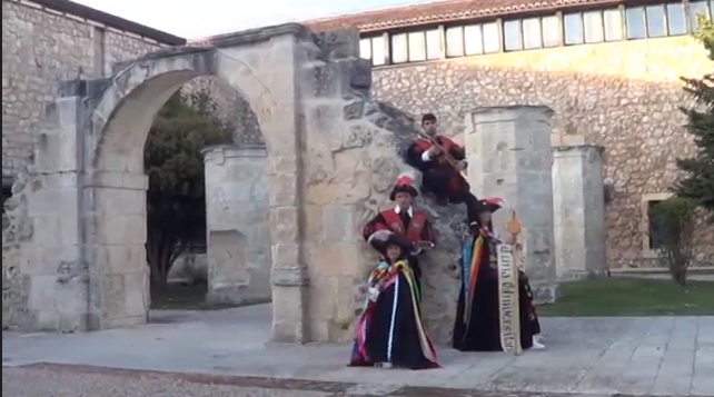 Un grupo de personas vestidas con túnicas coloridas posa ante un arco de piedra.