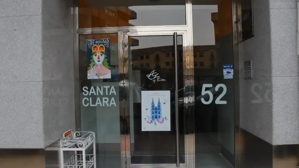 Puerta de Santa Clara en el número 52. La puerta de vidrio tiene carteles, una manija plateada y un edificio blanco detrás de ella.