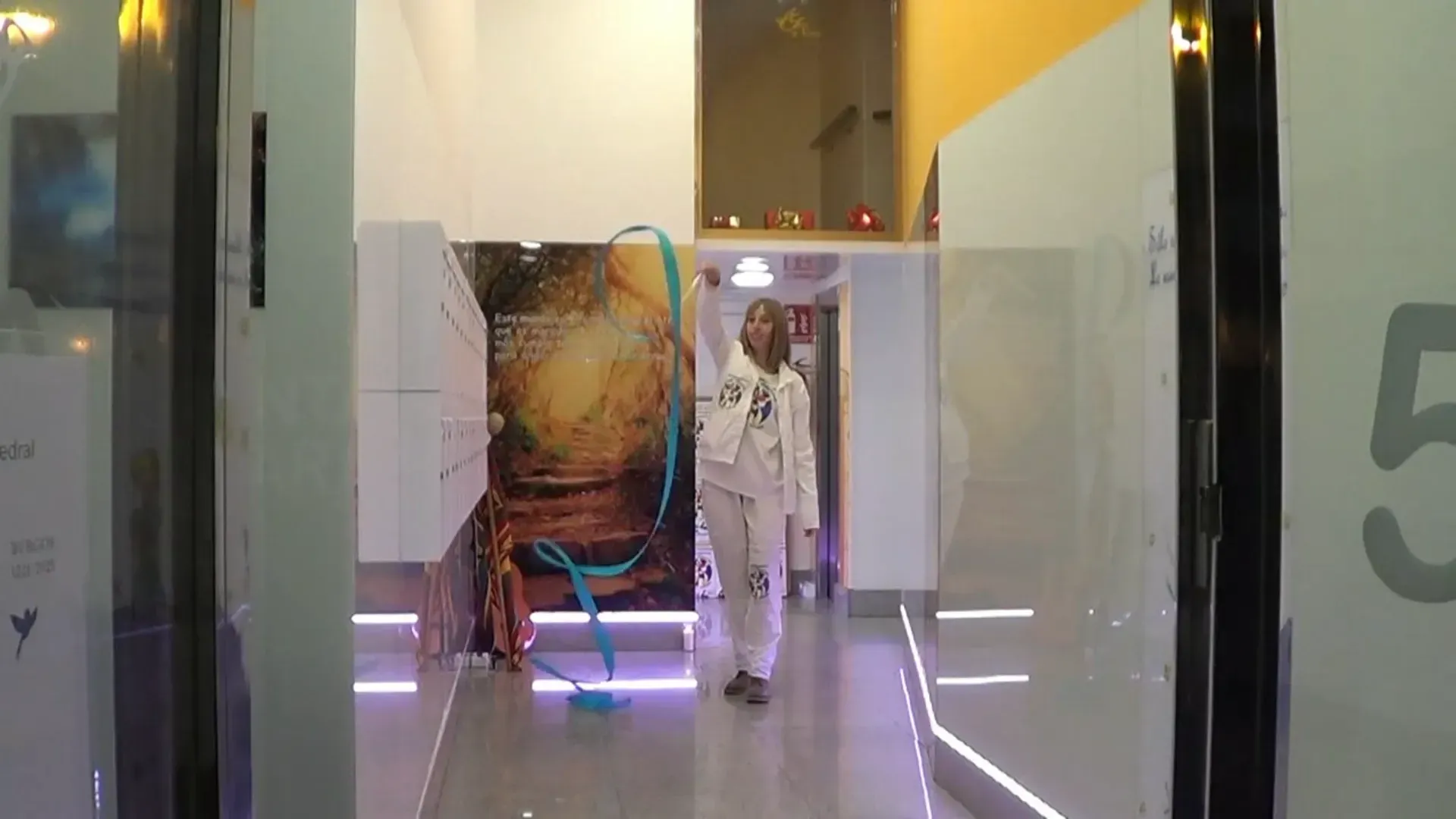 Una persona cruza una puerta con un objeto azul. El interior cuenta con una exposición y una iluminación brillante.
