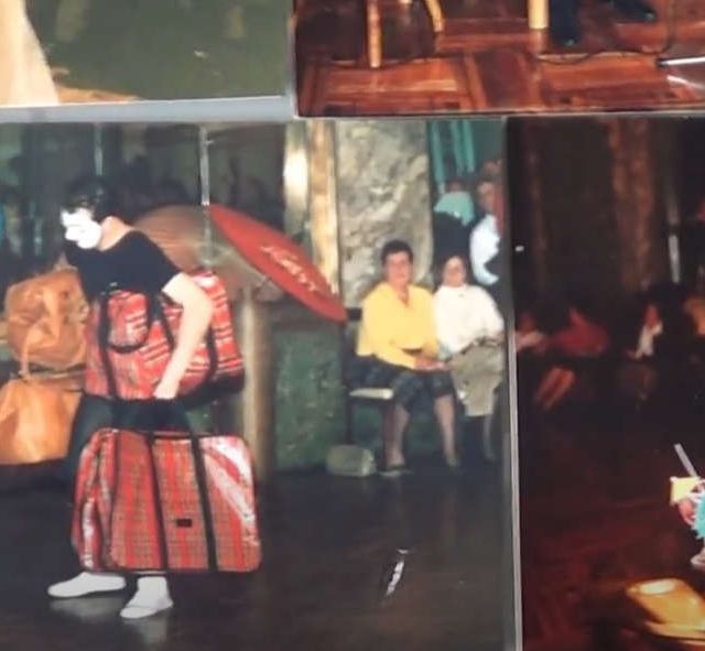 Un hombre que lleva equipaje camina entre la gente en una habitación con una combinación de colores rojo y marrón.
