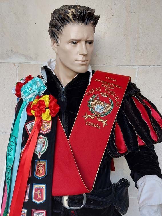 Maniquí con traje negro y rojo con fajín, banderas españolas y cintas, probablemente una exhibición histórica o cultural.