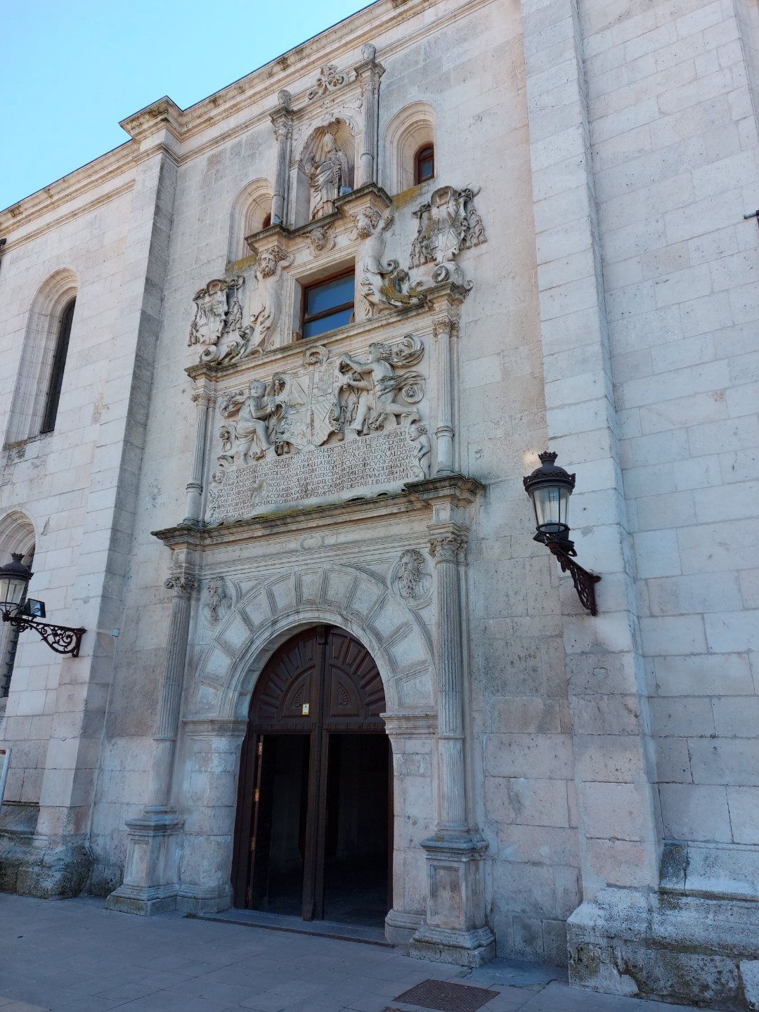 Fachada de iglesia de piedra con puerta arqueada, tallas ornamentadas y una pequeña ventana.