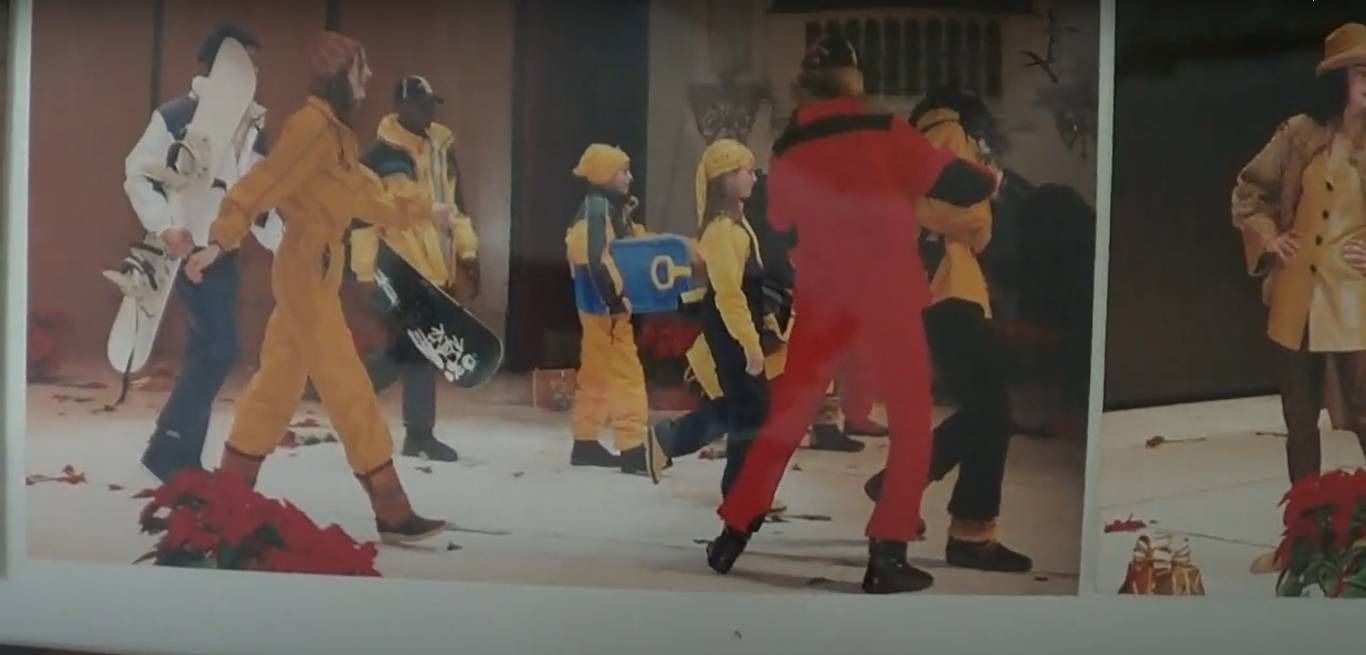 Personas vestidas con monos de colores brillantes caminan por una acera.