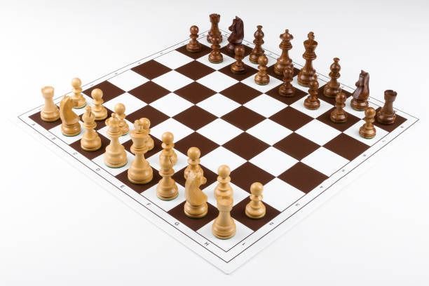 Tablero de ajedrez con casillas marrones y blancas y piezas de ajedrez de madera preparadas para una partida.