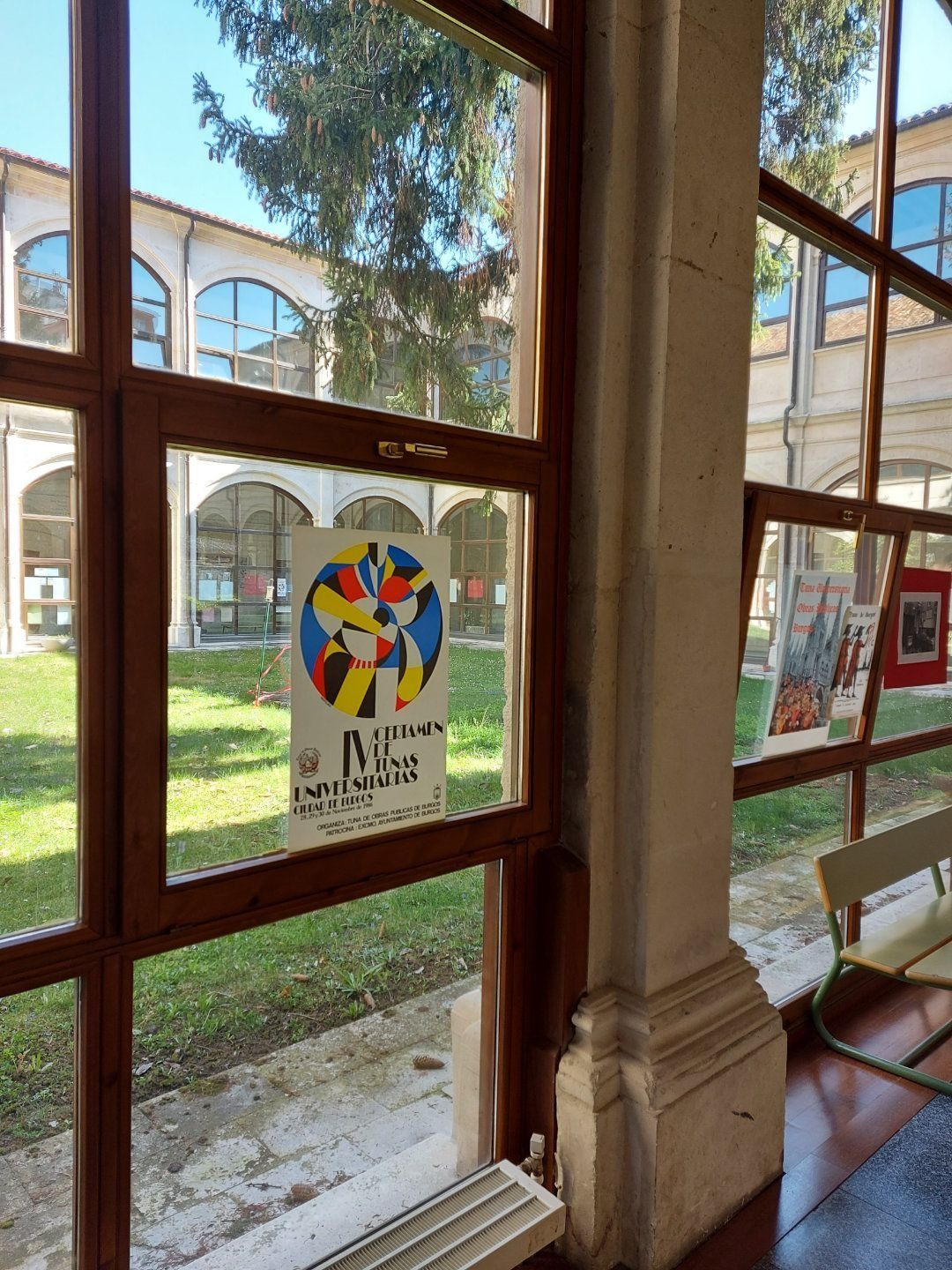 Cartel en ventana con diseño abstracto colorido, vista enmarcada del patio, día soleado.