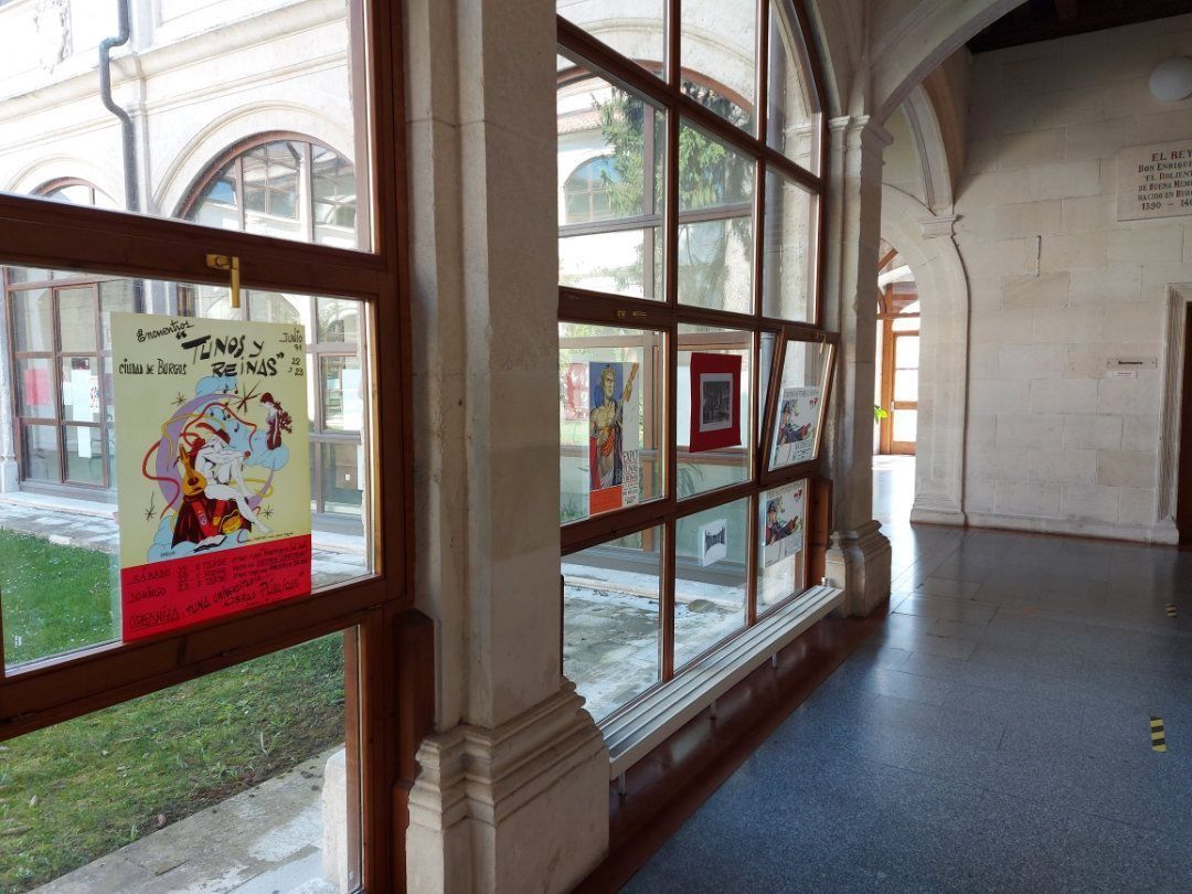 Pasillo con grandes ventanales que exhiben obras de arte, columnas de piedra y suelo de baldosas. La luz del sol entra a raudales.