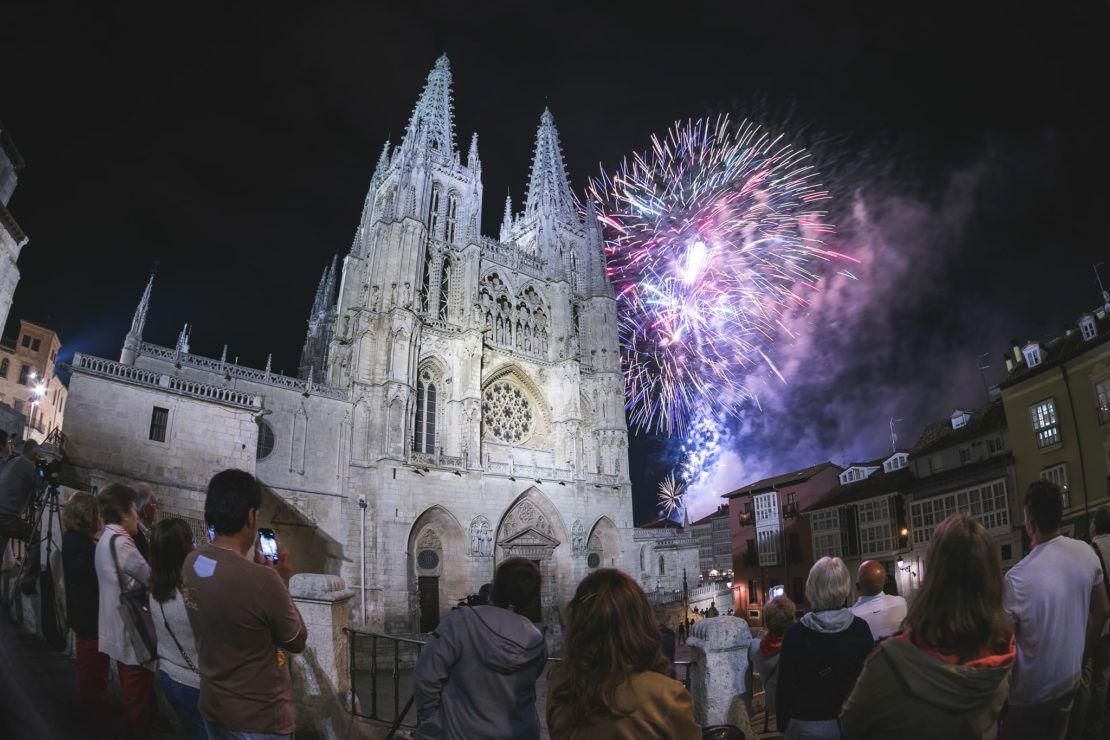 Los fuegos artificiales estallan sobre la Catedral de Burgos, ante una multitud que los observa por la noche.