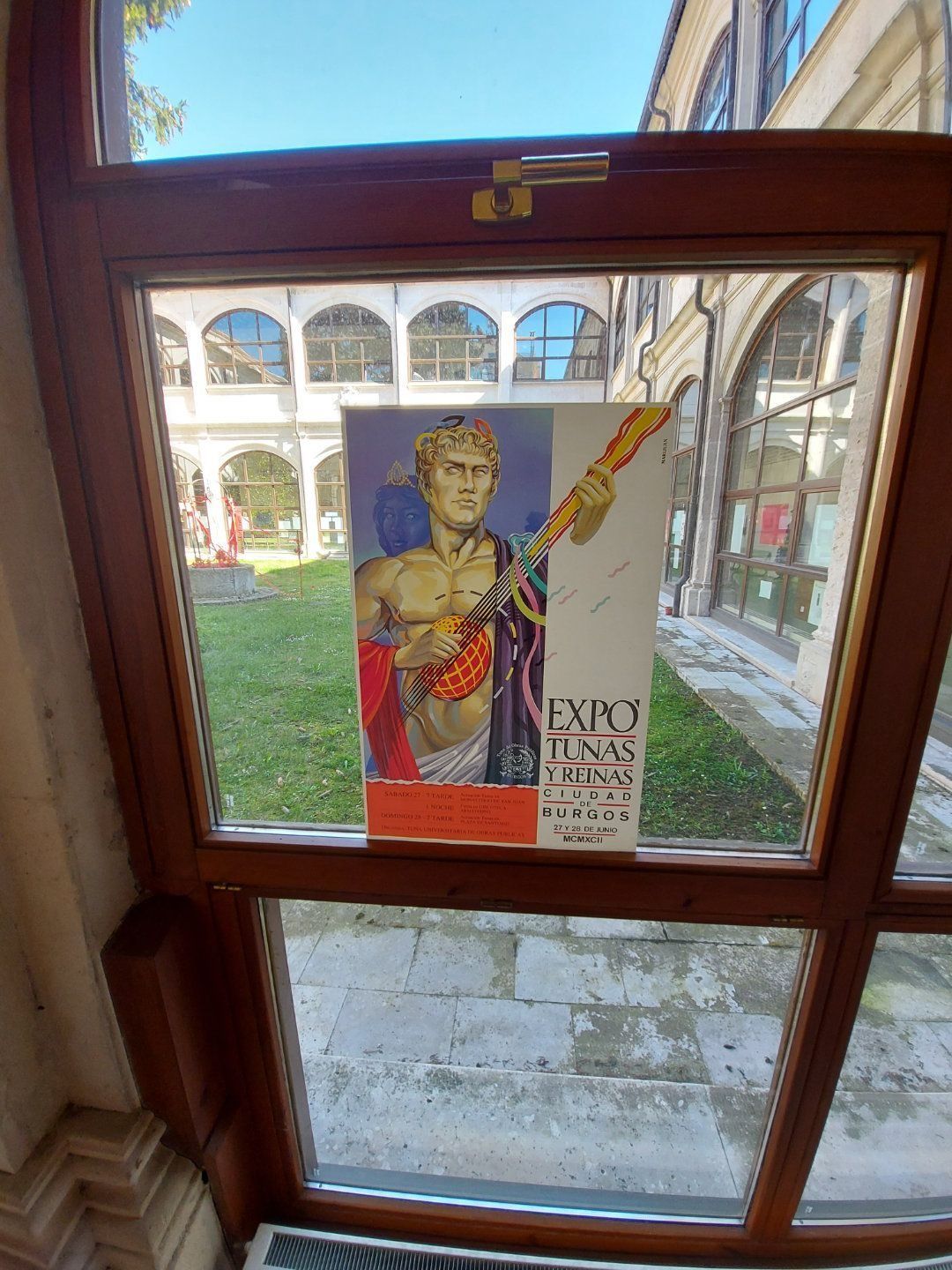 Cartel a través de una ventana: estatua romana, arte rojo y dorado con el texto 