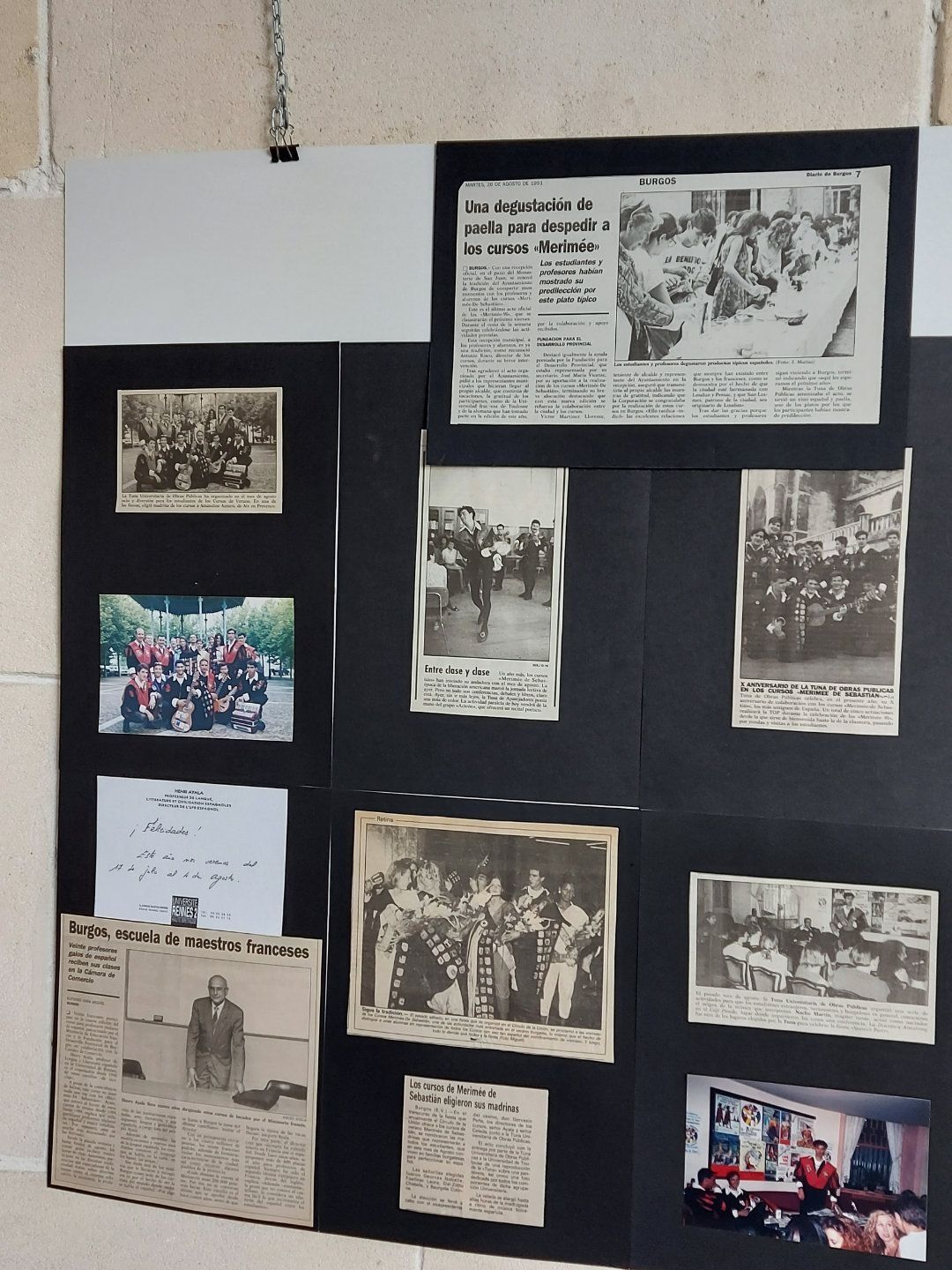 Tablón de anuncios con fotos antiguas y recortes de periódico. Fondo negro y encabezado blanco.