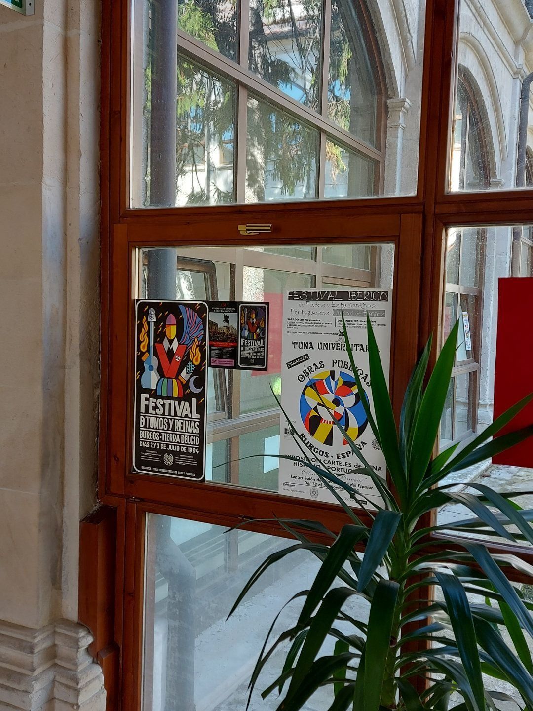 Carteles en una ventana. Uno muestra instrumentos musicales y el otro círculos de colores. Planta en primer plano.