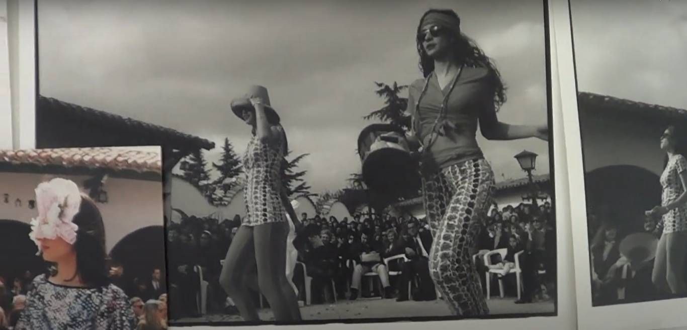 Fotografía en blanco y negro de dos mujeres vestidas de hippie bailando al aire libre mientras una multitud las observa.