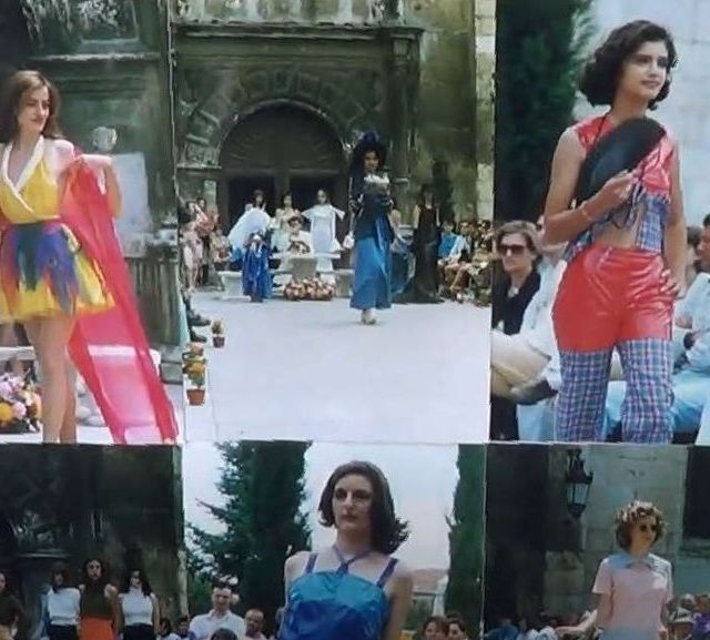 Desfile de moda al aire libre. Modelos con atuendos llamativos desfilan frente al edificio, mientras el público observa.