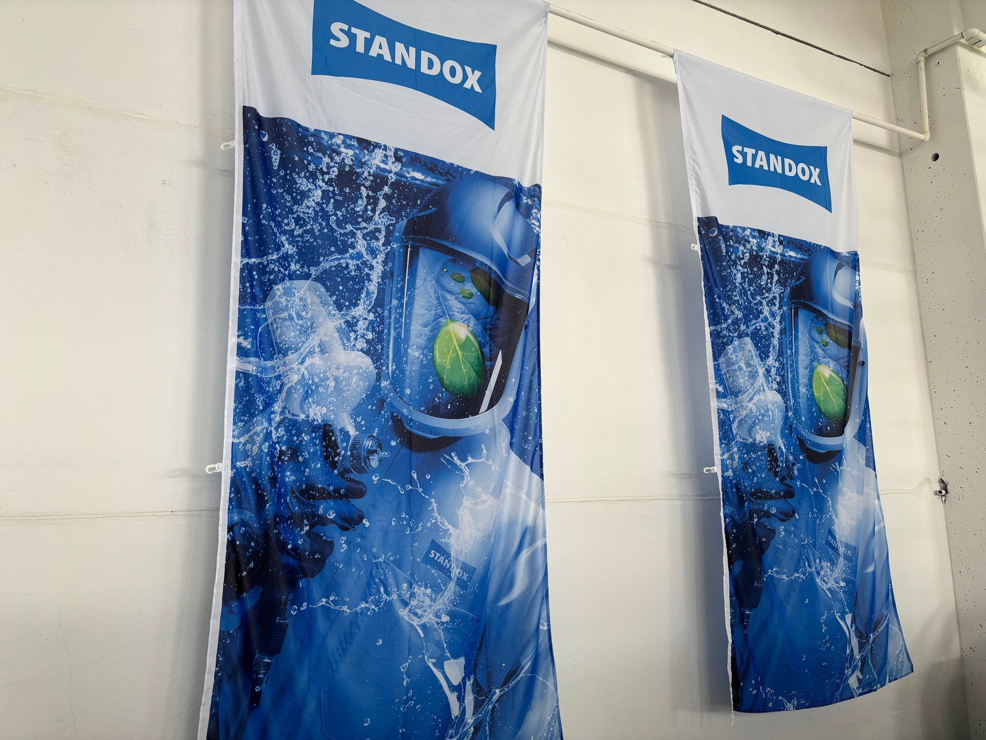 Zwei vertikale Banner mit einem blau-weißen Standox-Logo und einer Person mit Helm, die im Wasser untergetaucht ist.