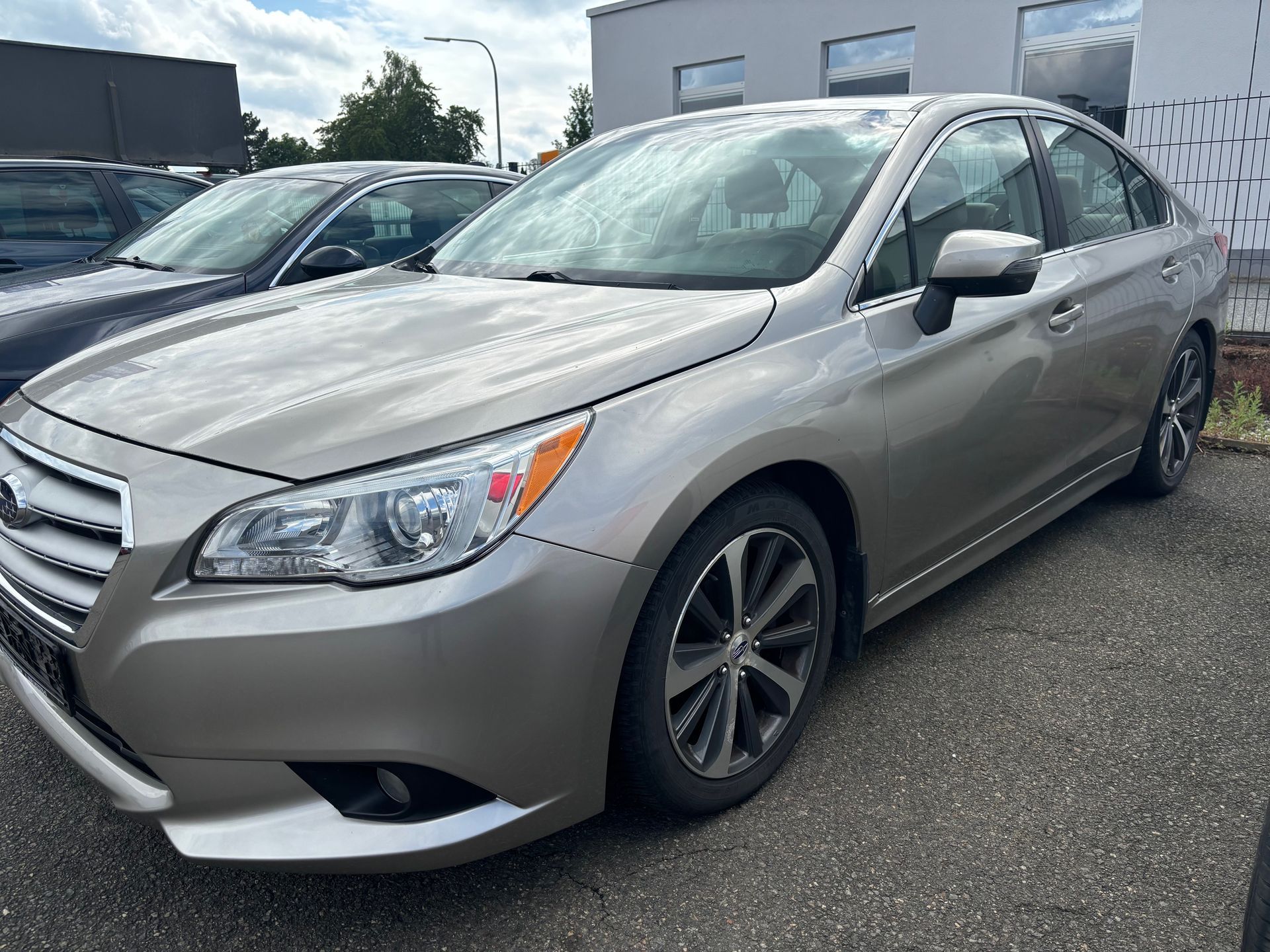 Hellbraune Subaru Legacy-Limousine auf Asphalt geparkt, sonniger Tag.