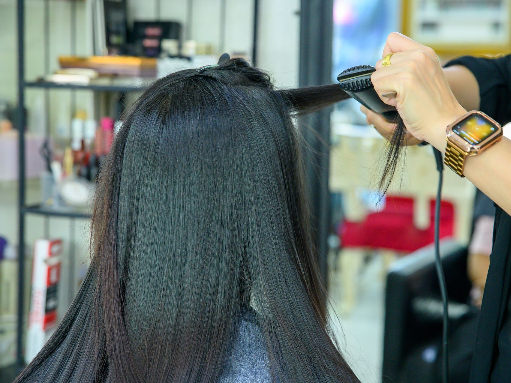 Coiffeur en train de lisser des cheveux noirs 