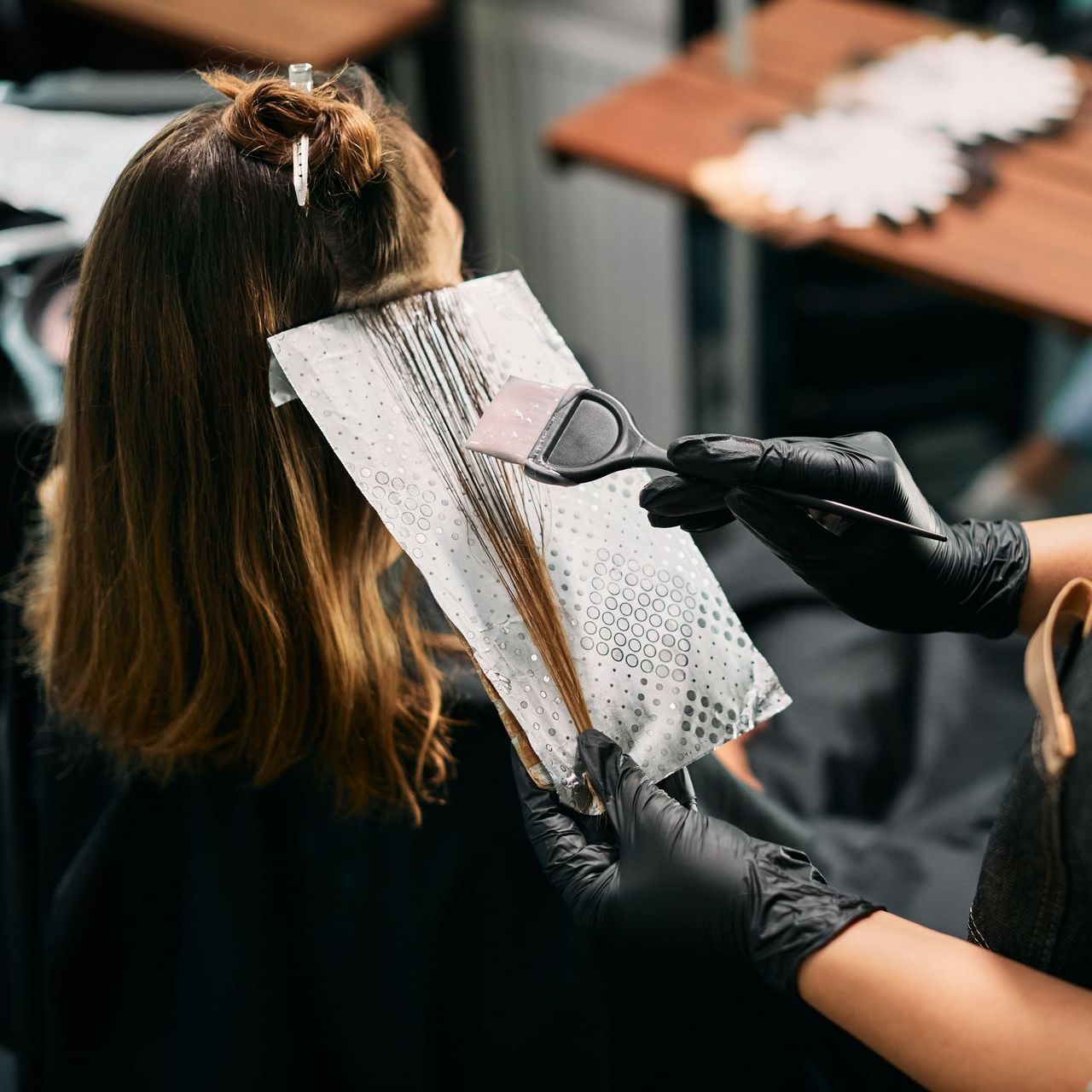 Coiffeur en train de faire une coloration sur une personne brune