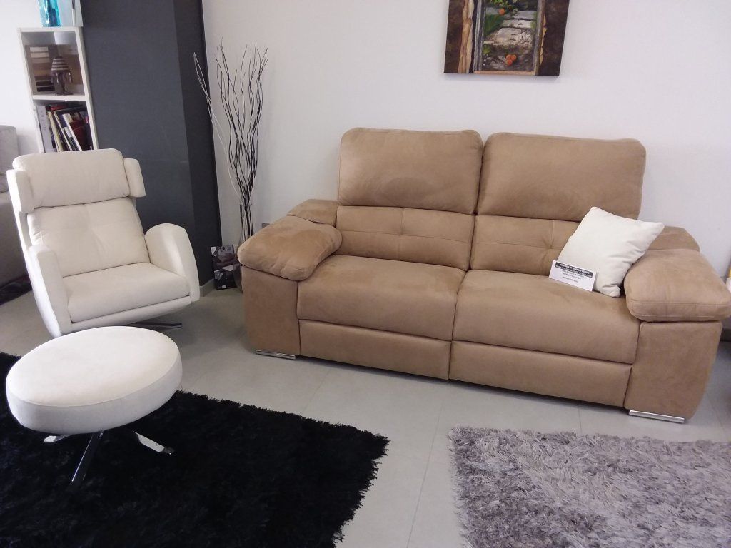 Sala de estar moderna con sofá beige, sillón blanco, otomana redonda y alfombras negras y grises.