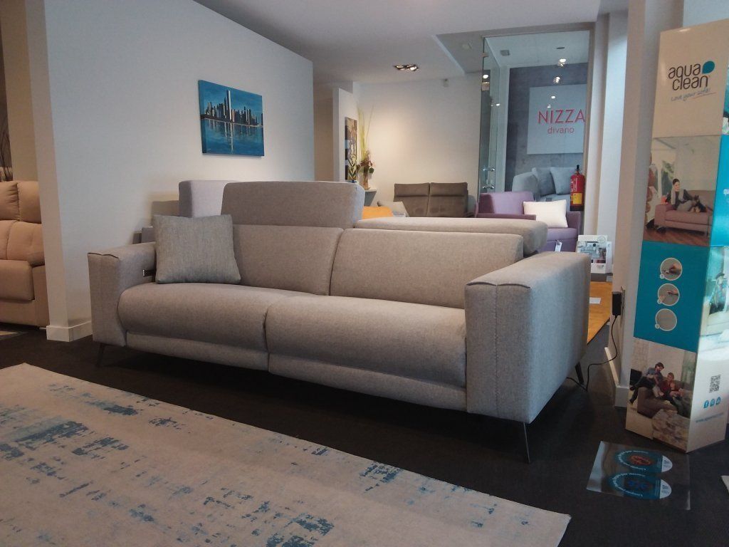 Sala de estar moderna con sofá beige, alfombra estampada, arte en la pared y vista al pasillo.