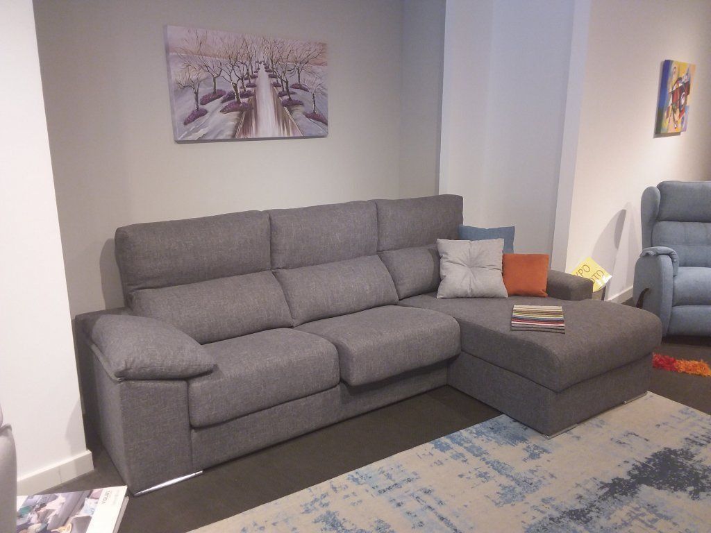 Sofá modular gris en una sala de estar con cuadros, cojines y una alfombra estampada.