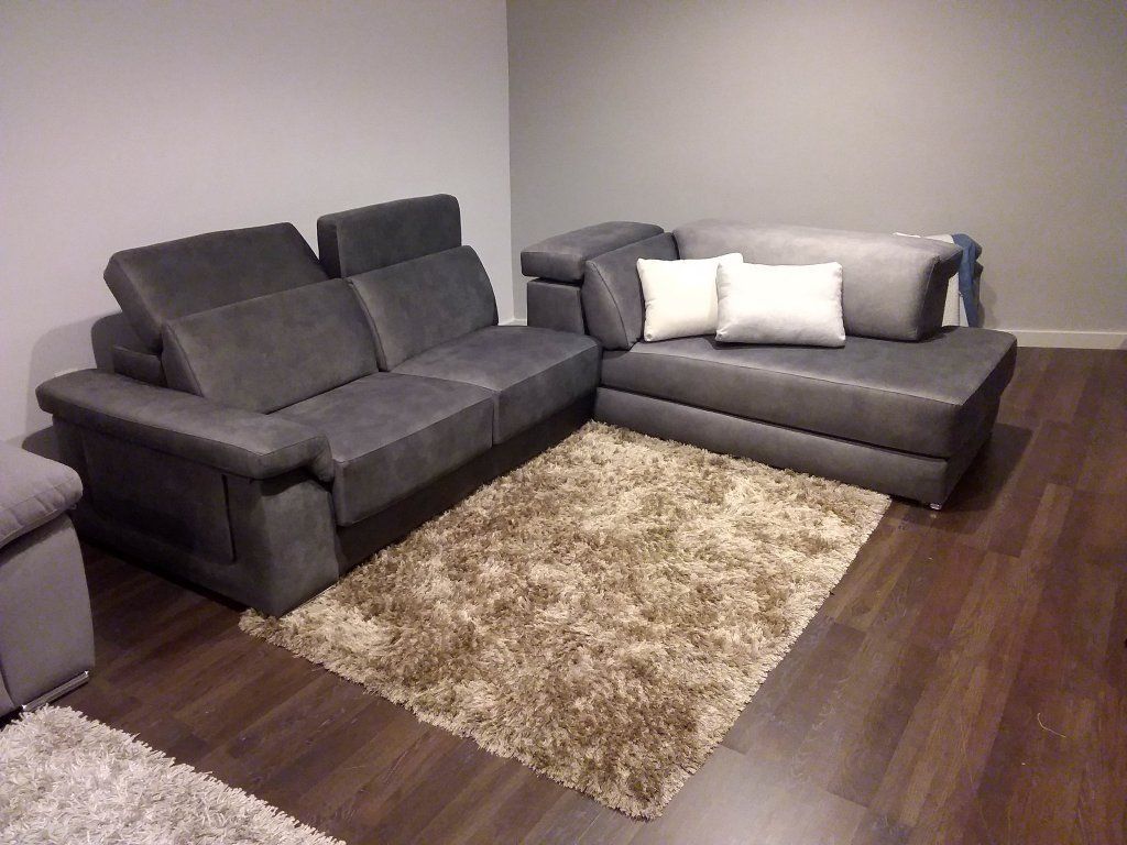 Sala de estar moderna con dos sofás grises, una alfombra de pelo largo y suelo de madera oscura.