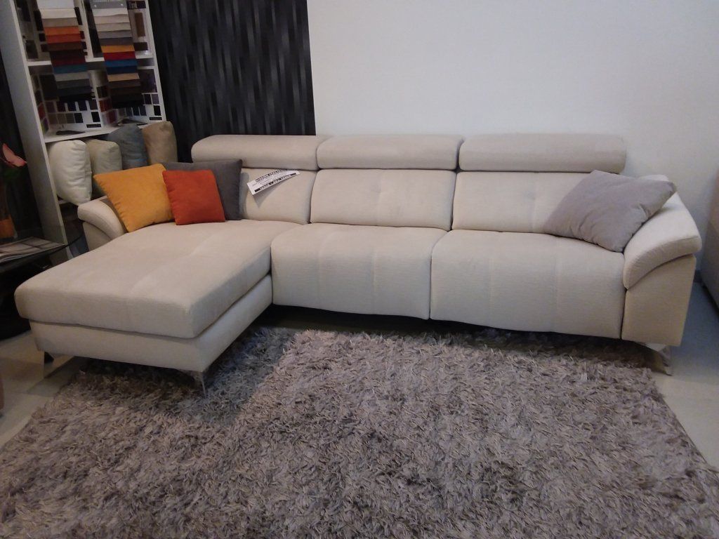 Sofá seccional beige con chaise longue sobre una alfombra gris de pelo largo en una sala de estar.