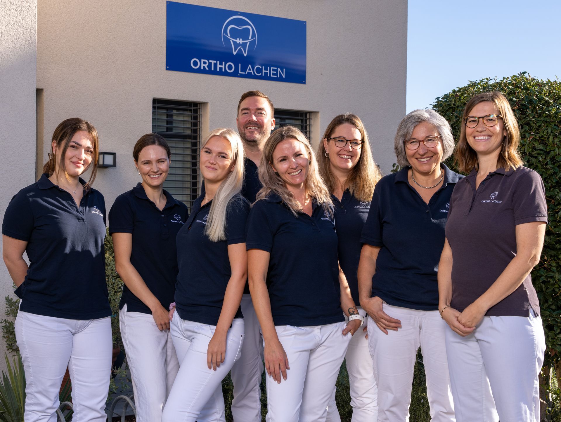 Eine Gruppe von Menschen posiert vor einem Gebäude für ein Foto.