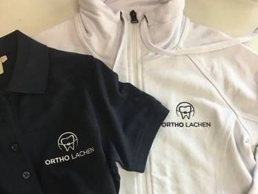 Zwei T-Shirts mit einem Logo liegen nebeneinander auf einem Tisch.