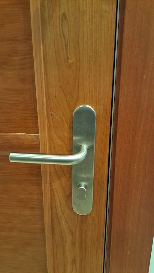Manilla plateada en una puerta de madera con placa para cerradura.