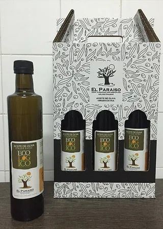 Una botella de aceite de oliva está al lado de una caja de aceite de oliva.