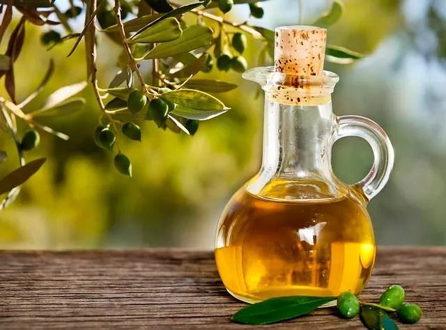 Una botella de aceite de oliva está sobre una mesa de madera.