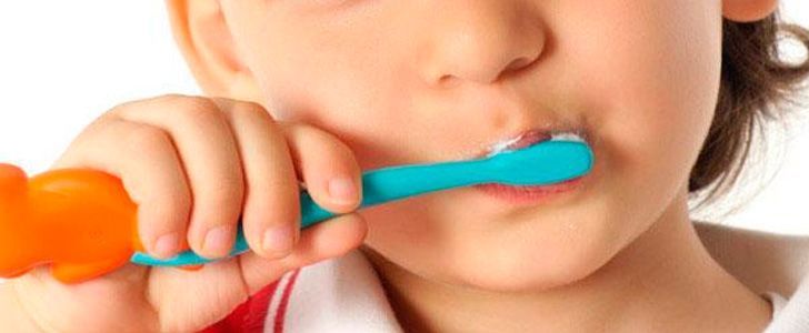 Una niña se cepilla los dientes con un cepillo de dientes de juguete.
