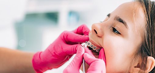 A una niña le están examinando los dientes un dentista.
