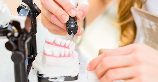 Un dentista está trabajando en un modelo de los dientes de una persona.