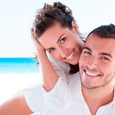 Un hombre lleva a una mujer a caballito en la playa.