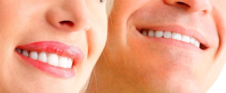 Un hombre y una mujer están sonriendo mostrando los dientes.