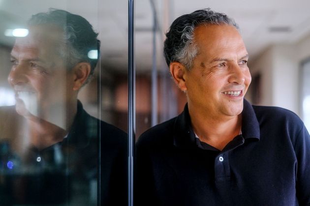 Un hombre está parado frente a una pared de vidrio y sonriendo.