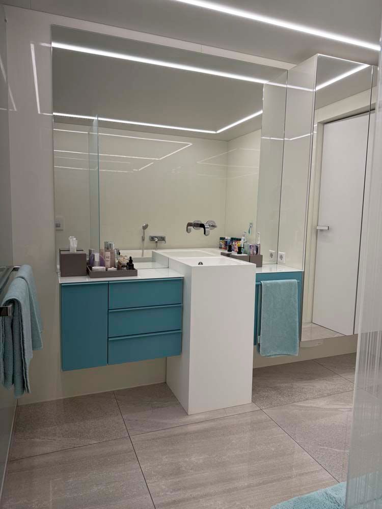 Ein Badezimmer mit Waschbecken, Spiegel und blauen Schränken.