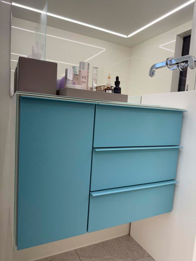 Ein Badezimmer mit einem blauen Waschtisch und einem Spiegel