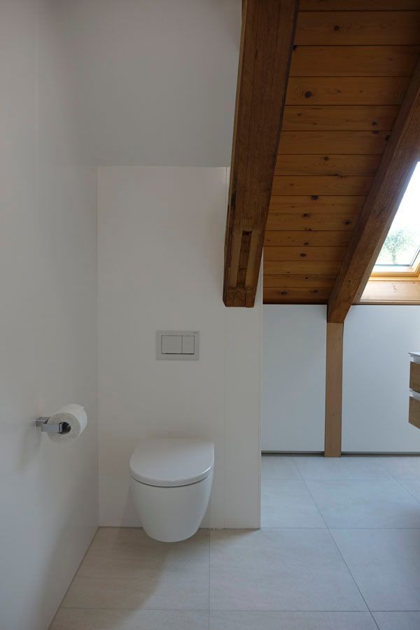 Im Badezimmer mit Holzdecke befindet sich eine Toilette.