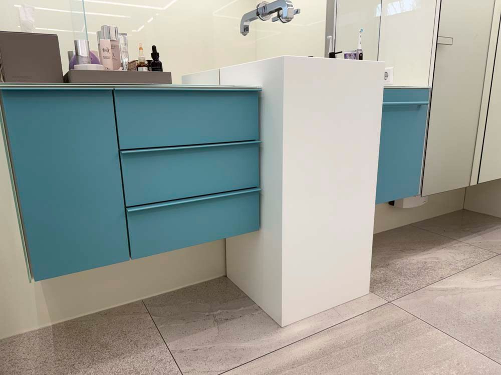 Ein Badezimmer mit blauen Schränken und einem weißen Waschbecken