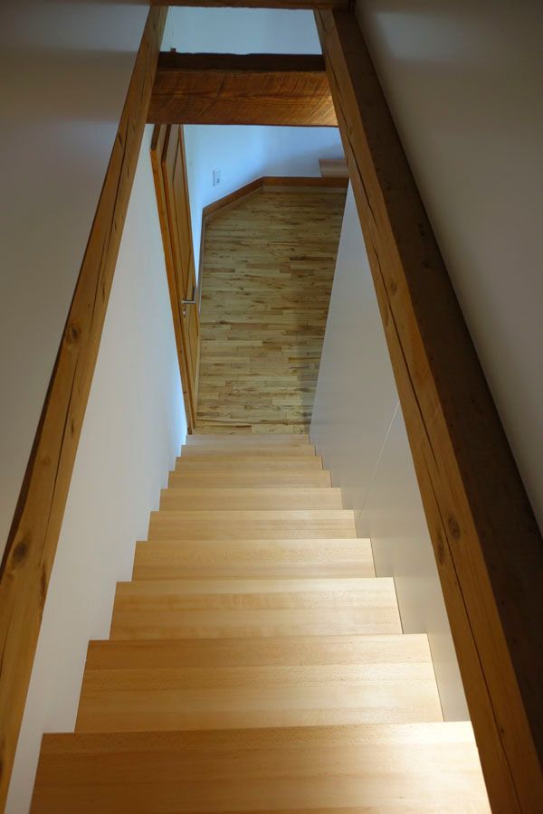 Eine Holztreppe führt hinauf zu einem Raum mit Holzboden.