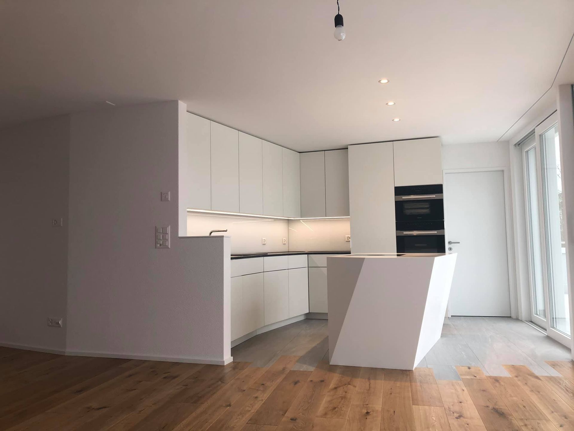 Eine leere Küche mit weißen Schränken und Holzböden.