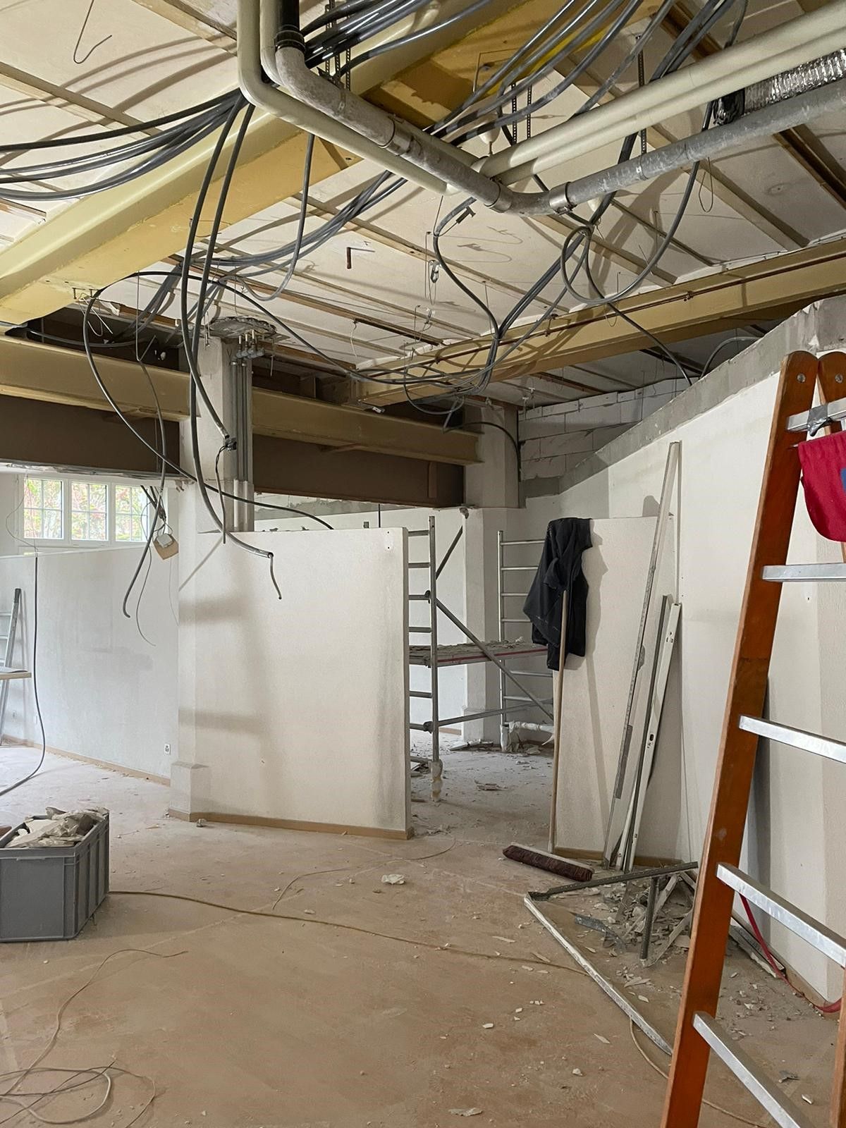 Ein leerer Raum mit einer Leiter und einem Haufen Kabel, die von der Decke hängen.