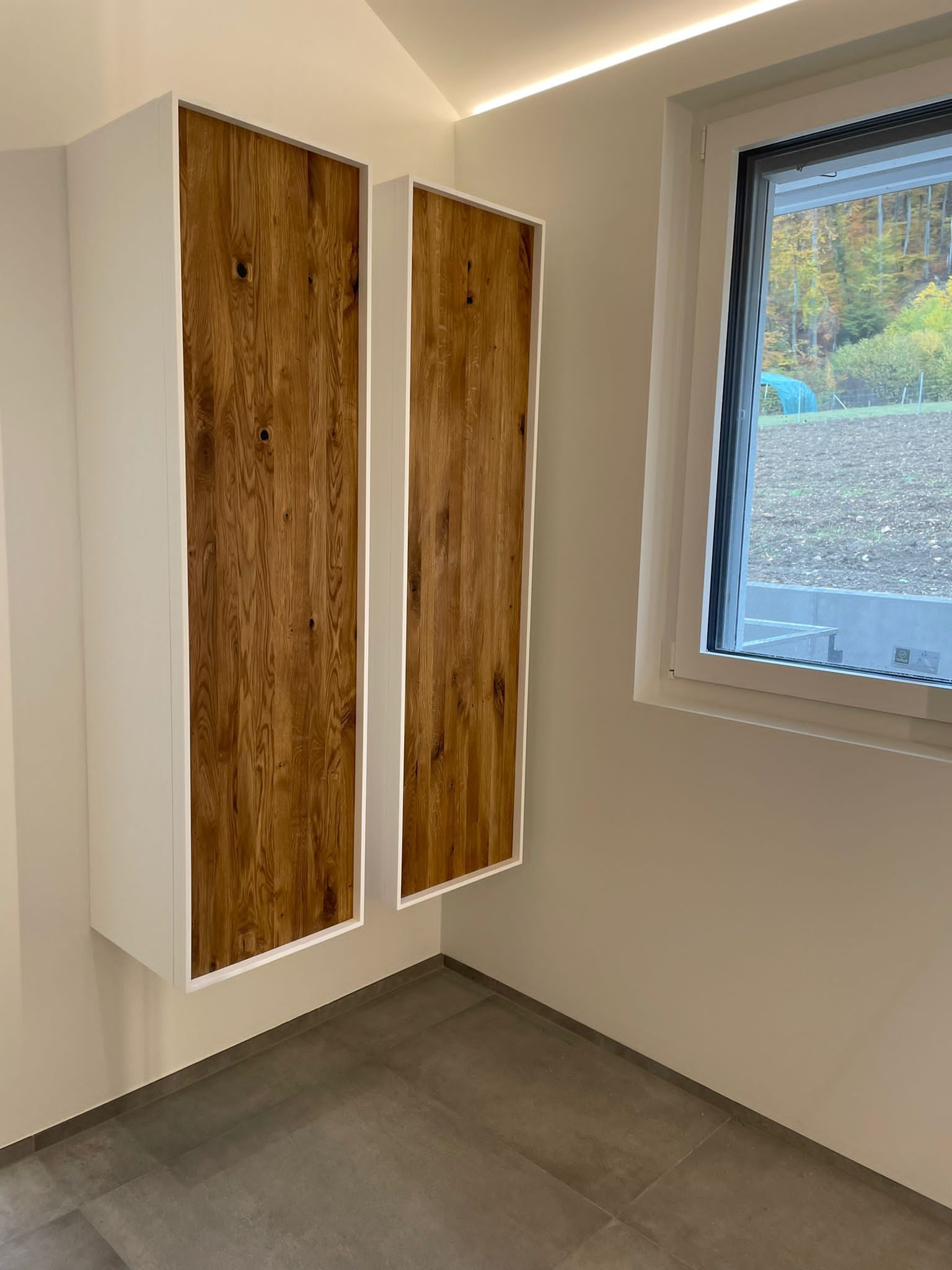 Ein Raum mit zwei Holzschränken und einem Fenster.