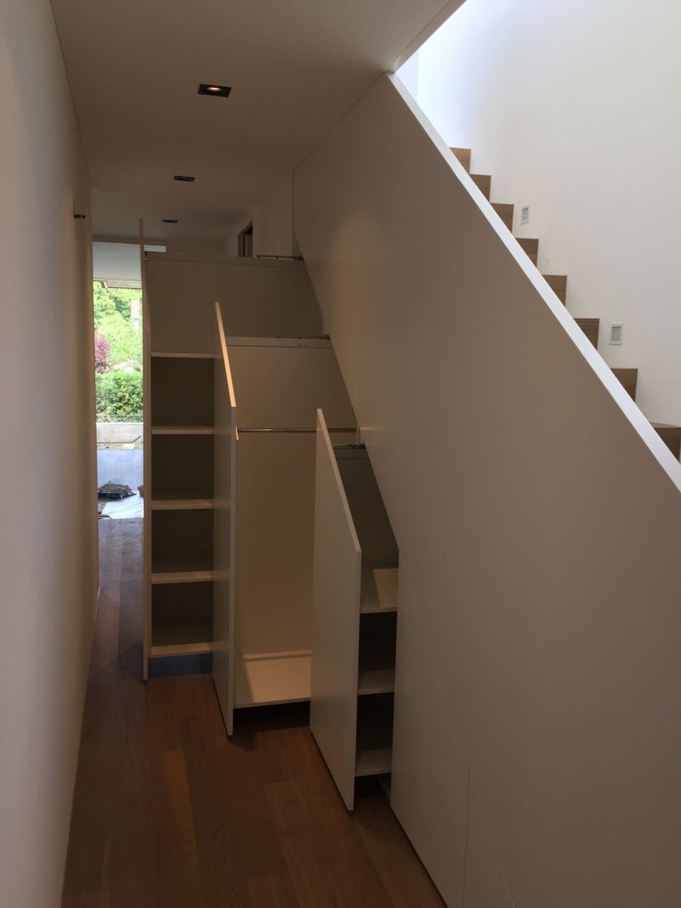 Ein Flur mit einer Treppe und Regalen darunter