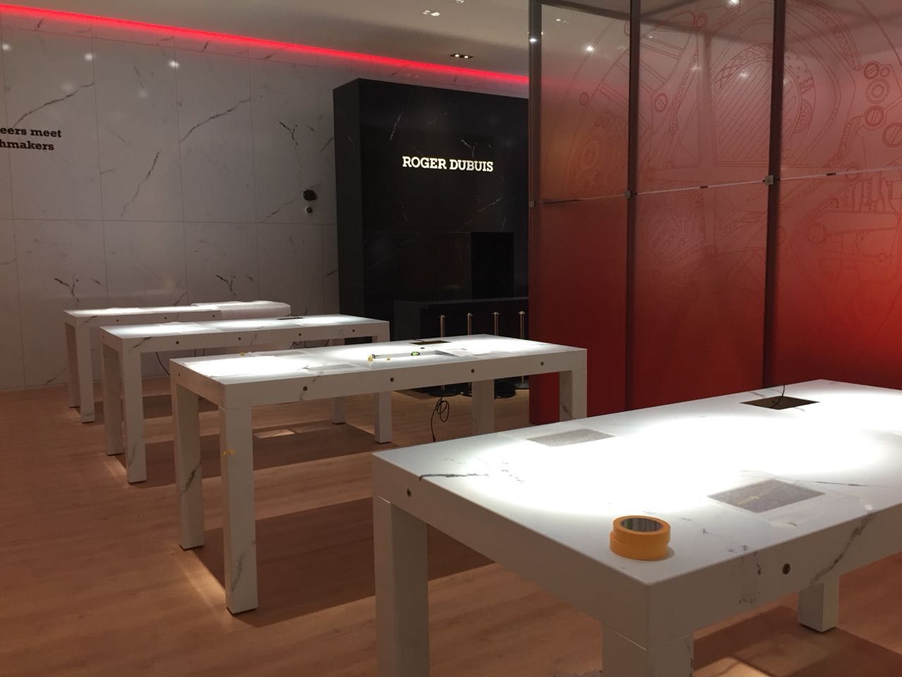 Eine Reihe weißer Tische in einem Raum mit roter Wand